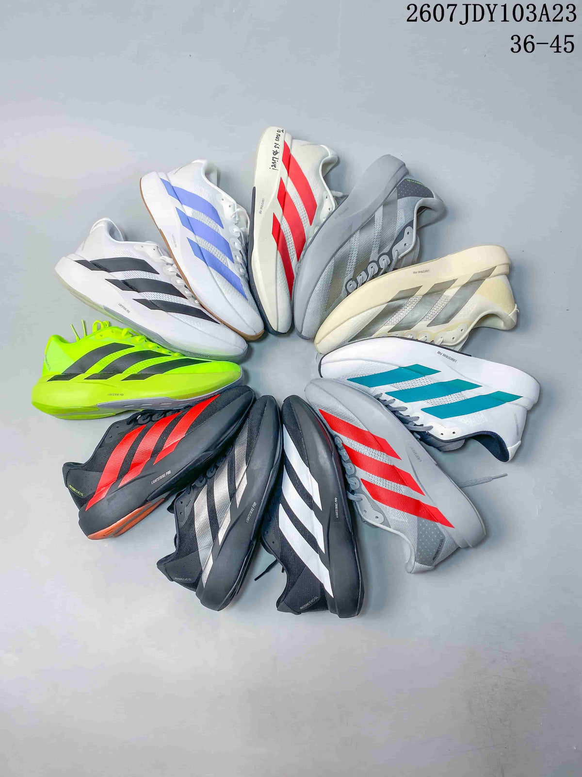 Several adidas Adizero sneakers arranged together in white, black, neon green, red, blue, turquoise, gray, and cream colorways.