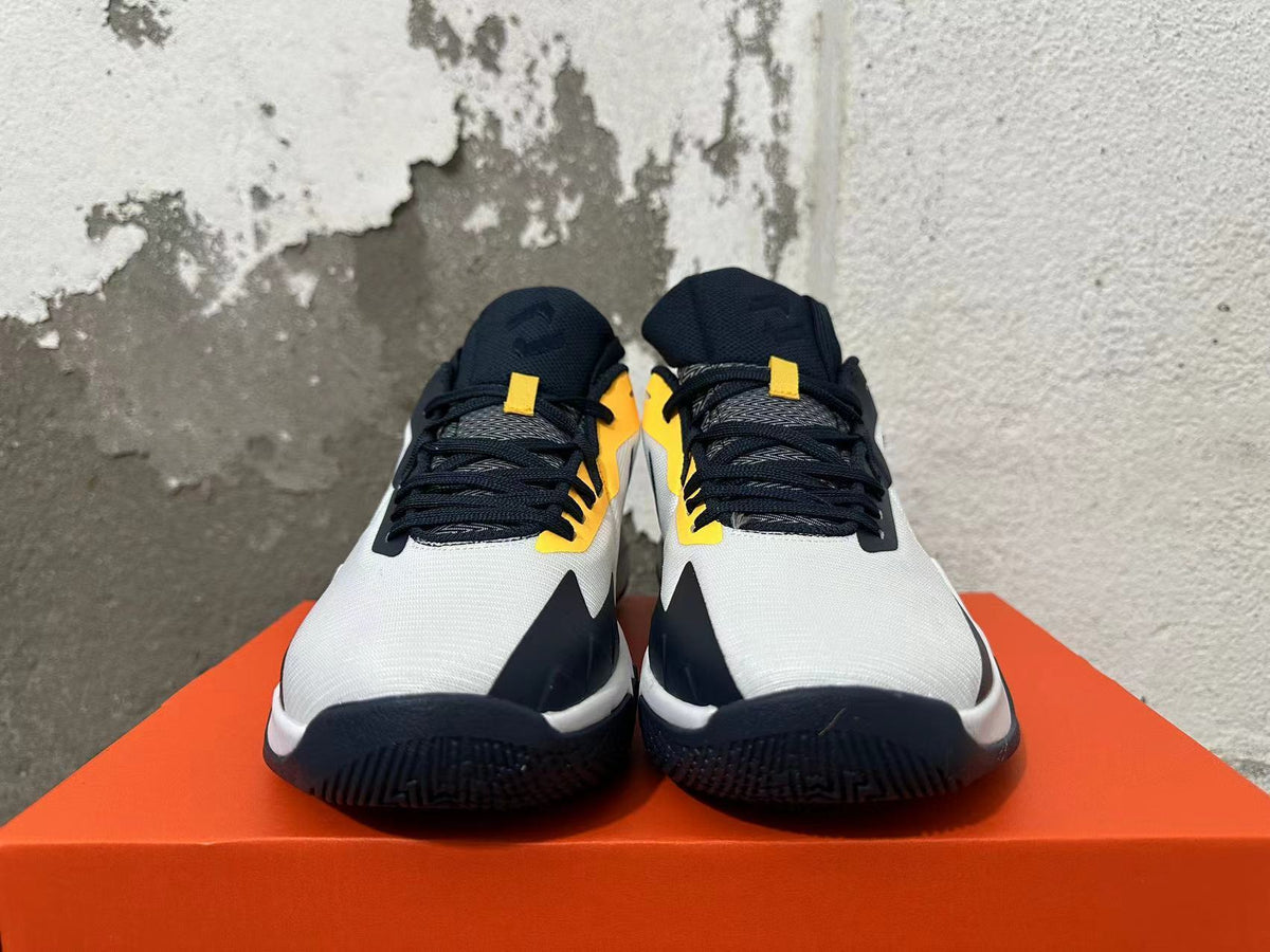 Front view of white, navy and yellow Nike basketball shoes with dark laces