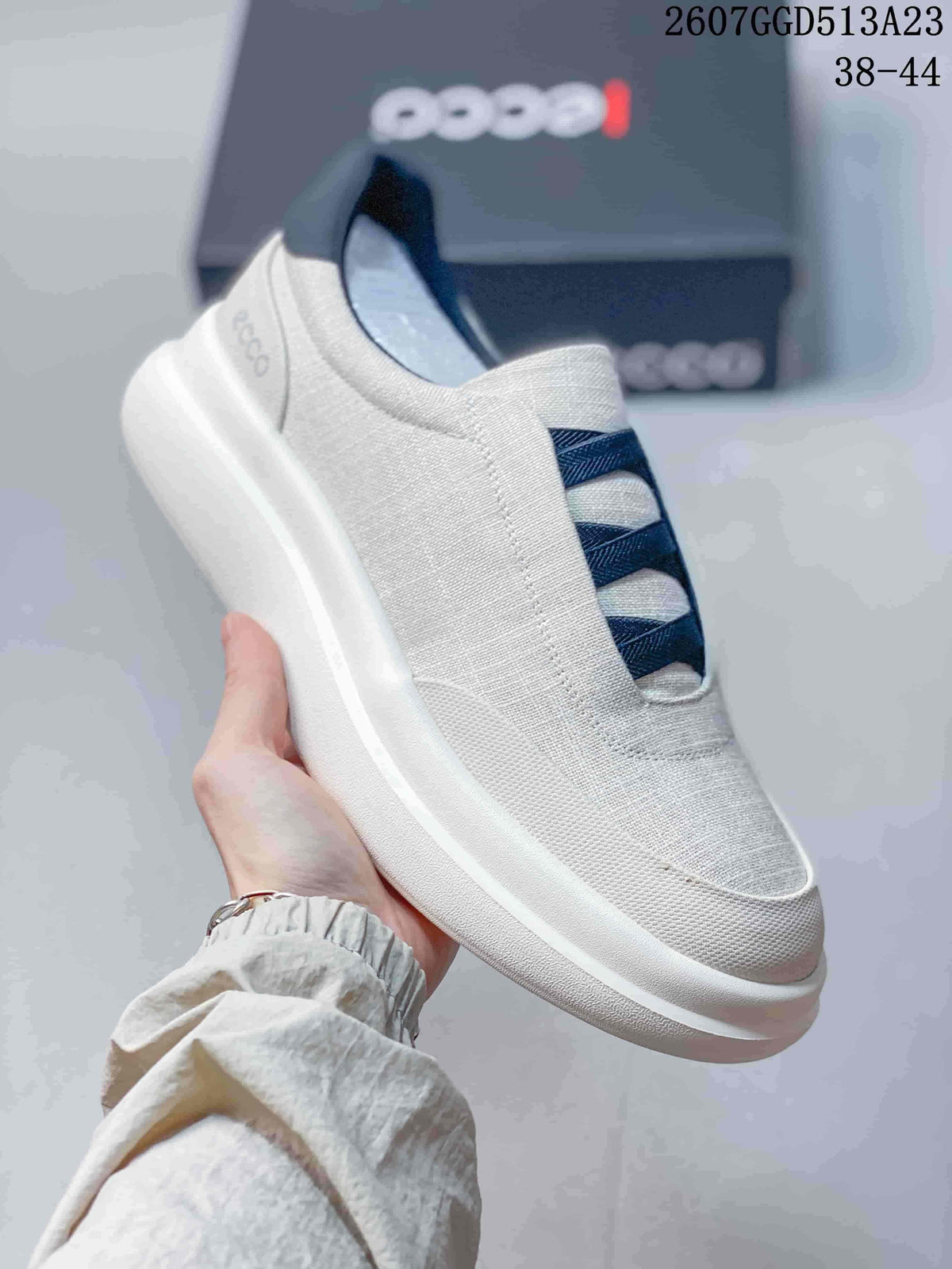 Side view of a white ECCO slip-on sneaker with dark blue straps, heel detail and thick white outsole.