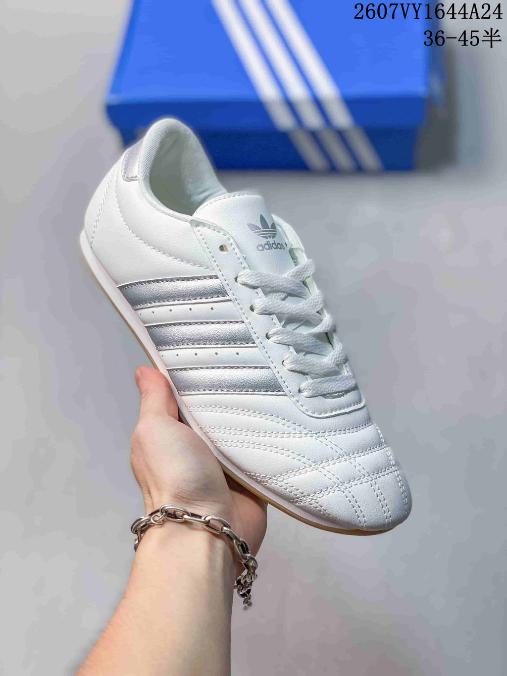 Angled side view of the white sneaker with silver stripes and a gum-colored sole.