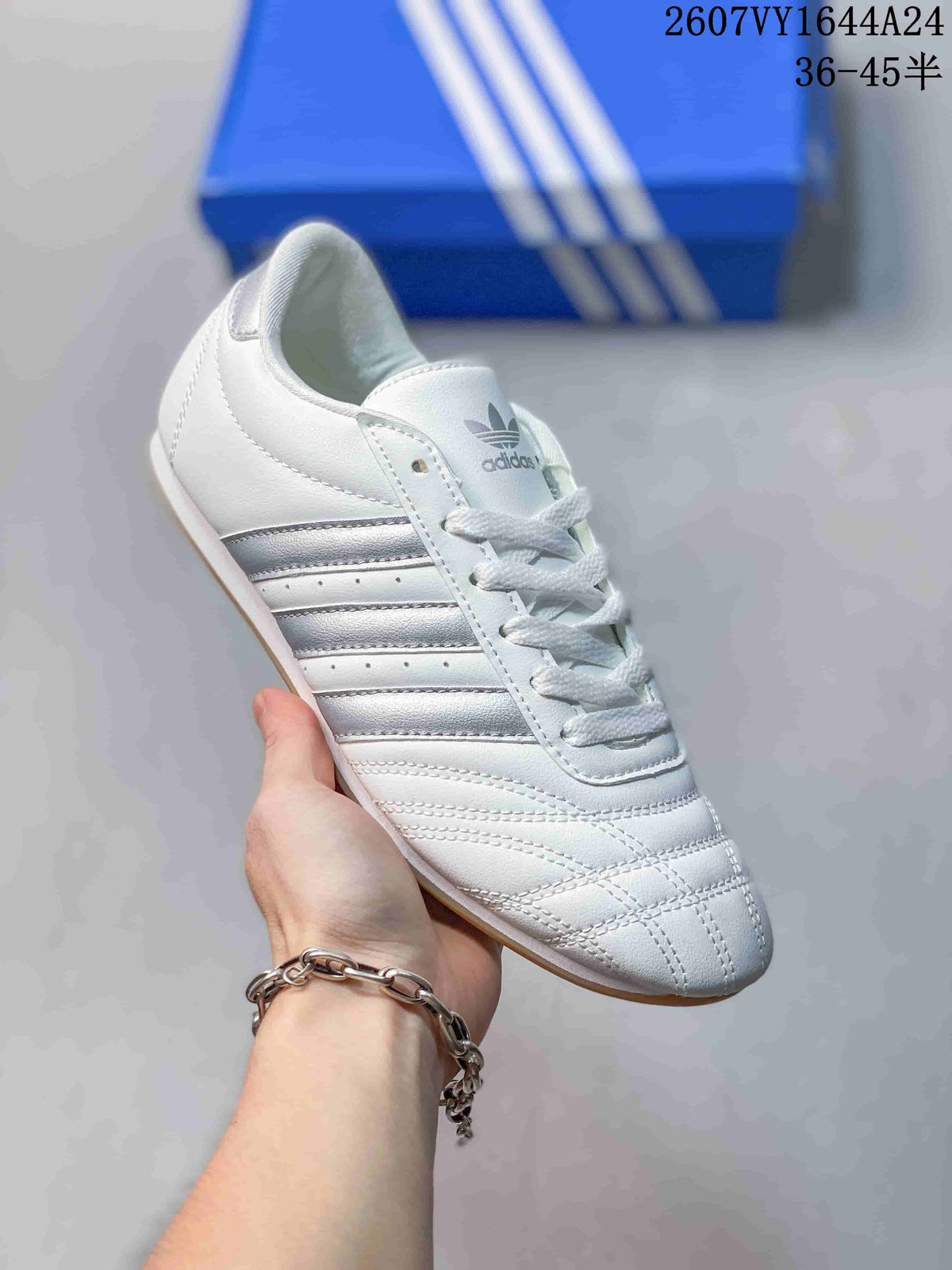 Angled side view of the white sneaker with silver stripes and a gum-colored sole.