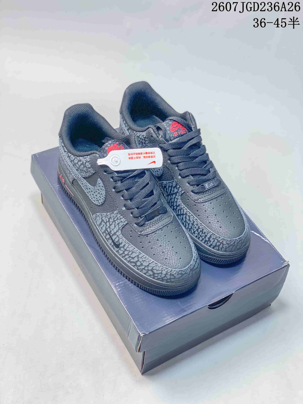 Pair of dark gray low-top sneakers shown on a shoebox, with patterned overlays, red accents, and a visible source size range marking.