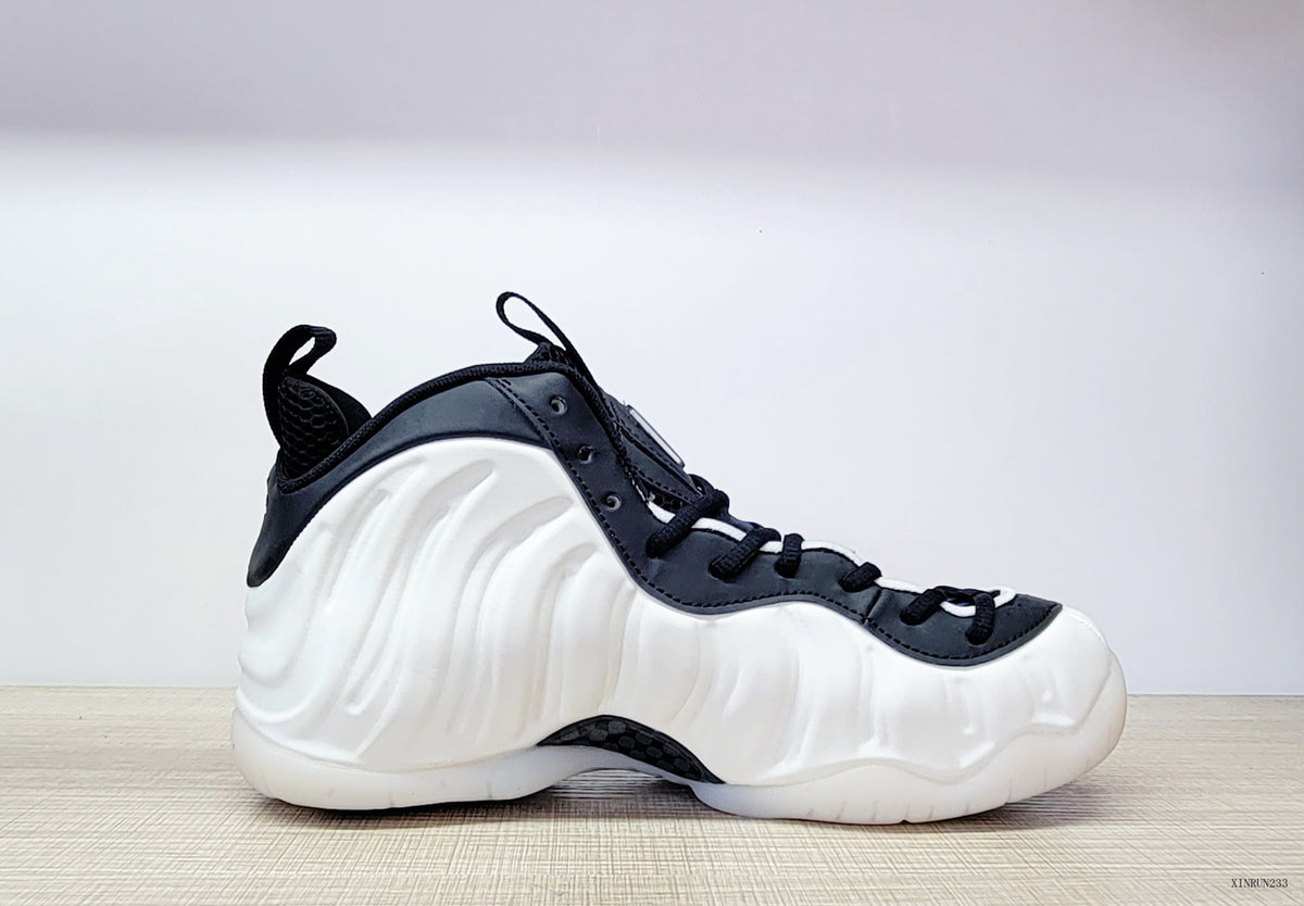 Side view of a white Nike Air Foamposite One high-top with black laces and collar