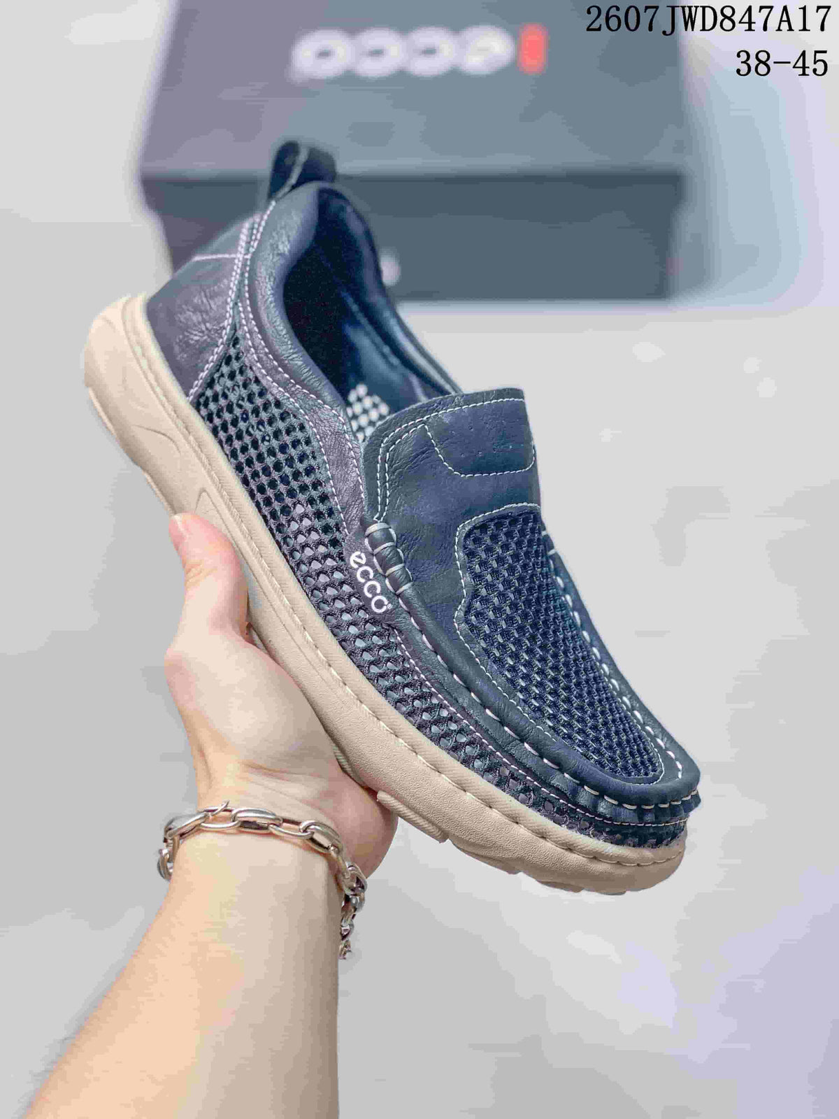 Close-up side view of a dark navy ECCO slip-on shoe showing mesh panels, stitched detailing, pull tab and light outsole.