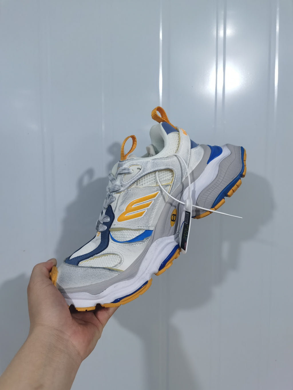 Top and side view of the New Balance 9174 sneaker showing the mesh sections, layered panels, orange detailing and blue trim.