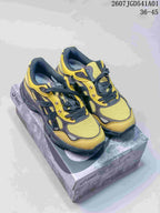 Pair of yellow and charcoal ASICS GEL-NYC 2.0 sneakers on a shoebox