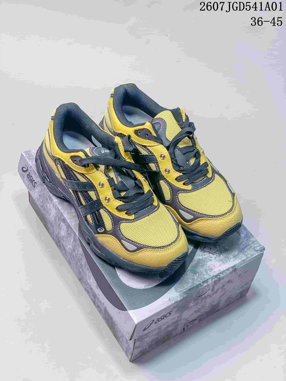 Pair of yellow and charcoal ASICS GEL-NYC 2.0 sneakers on a shoebox
