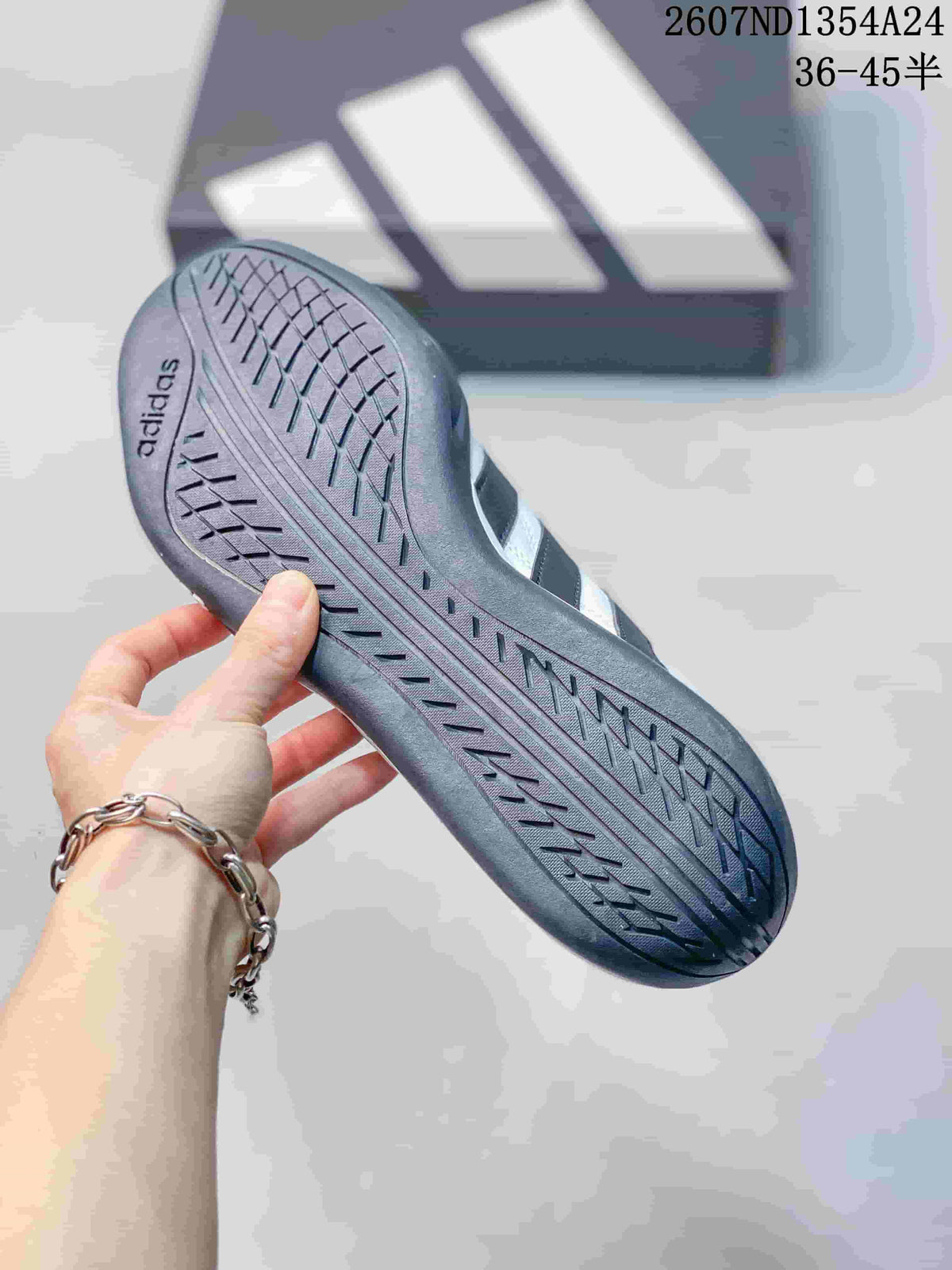 Close view of the textured dark outsole of a white and black adidas sneaker.