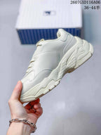 Side profile of the plain cream beige sneaker showing the layered chunky sole and stitched panels.