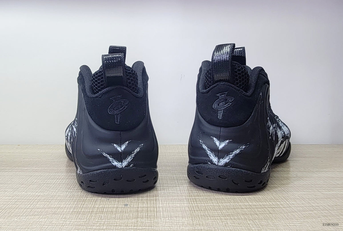 Rear view of black high-top sneakers with white V-shaped heel graphics