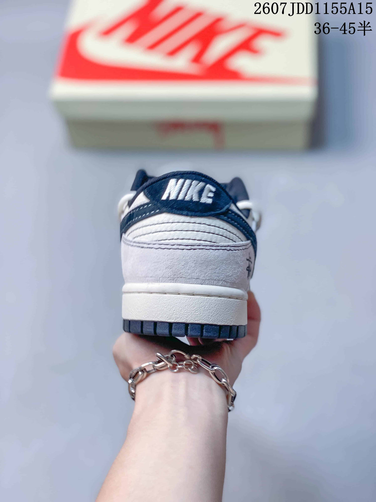 Rear view of a Nike SB Dunk Low sneaker showing the navy collar, white heel panel, layered stitching, and dark outsole edge.