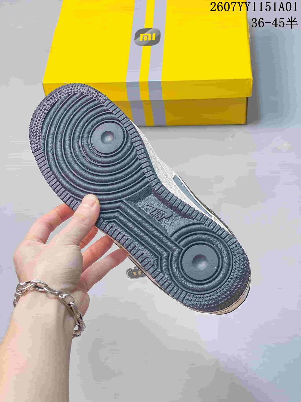 Close-up of the dark gray patterned outsole and yellow shoe box.