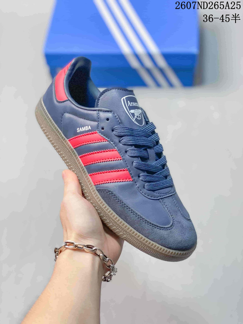 Angled side view showing the navy upper, red stripes, Samba text, lace-up front, and gum-colored outsole.