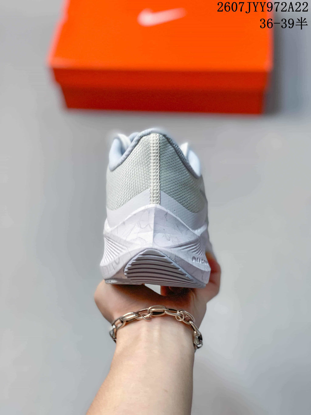 Rear view of a light gray Nike running shoe showing the mesh heel, padded collar, midsole, and outsole tread.