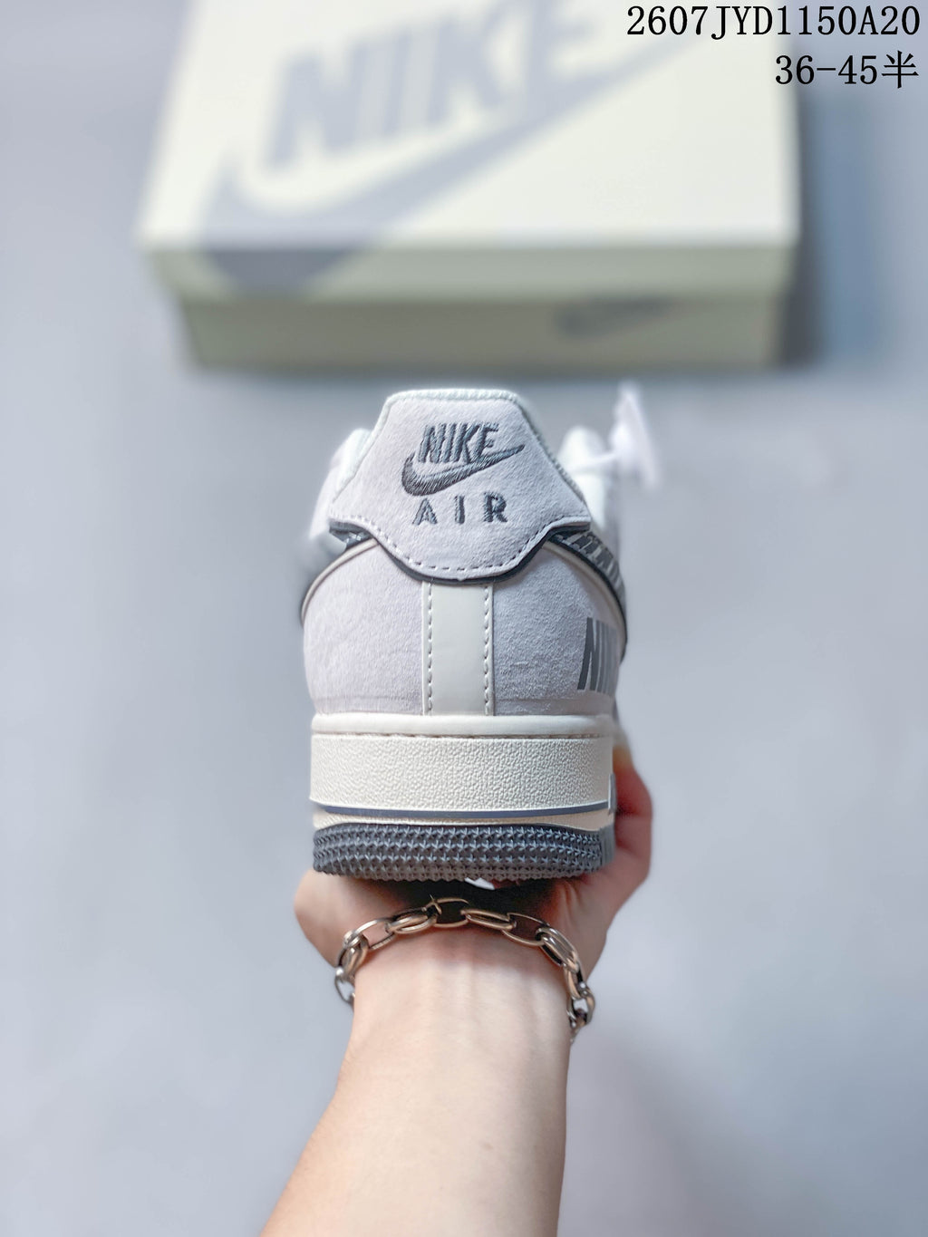 Rear view of a white and gray sneaker showing the Nike Air heel label, padded collar, midsole, and gray outsole.