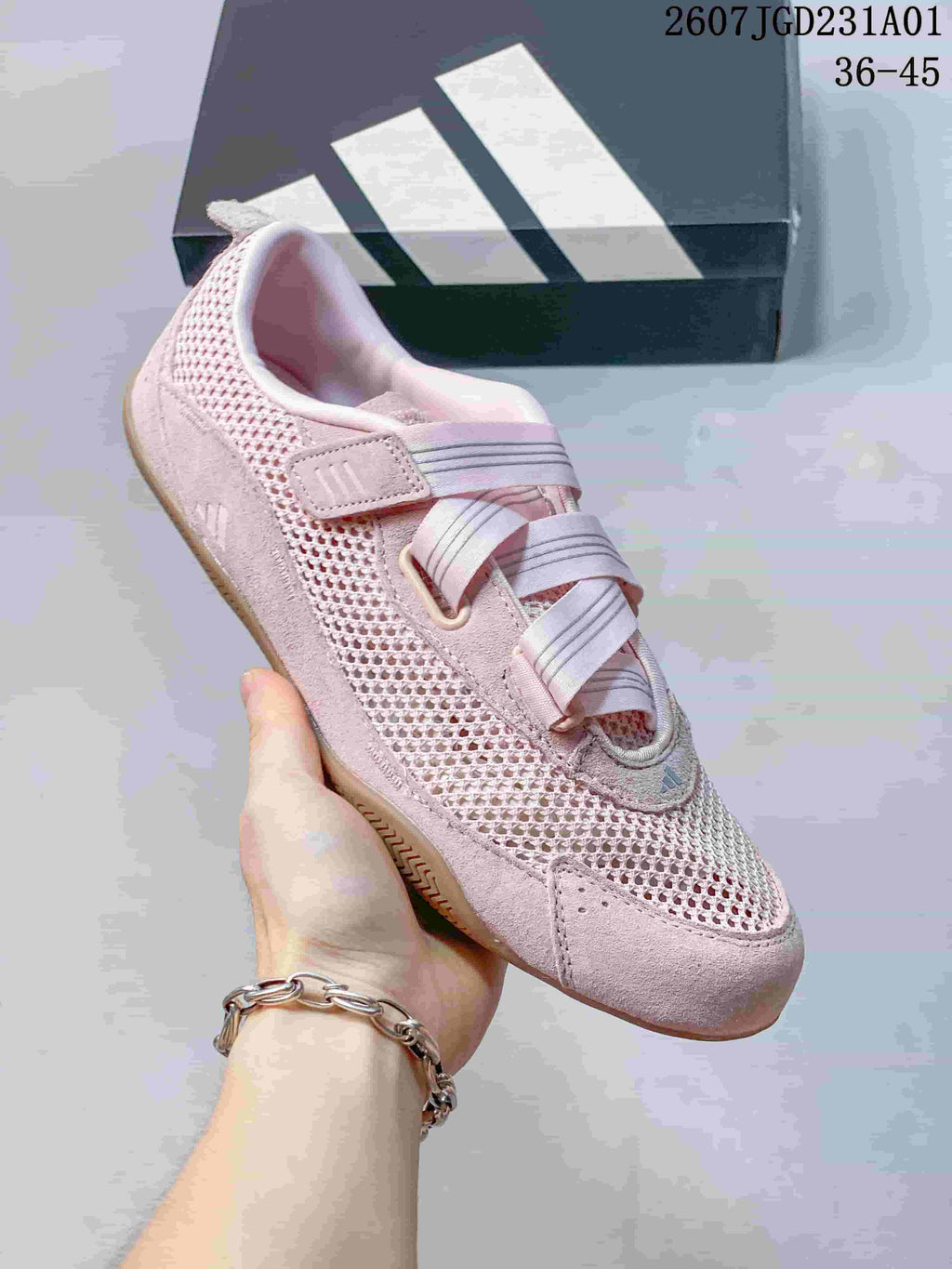 Angled view of a pink Adidas sneaker with mesh-look panels and crossed straps