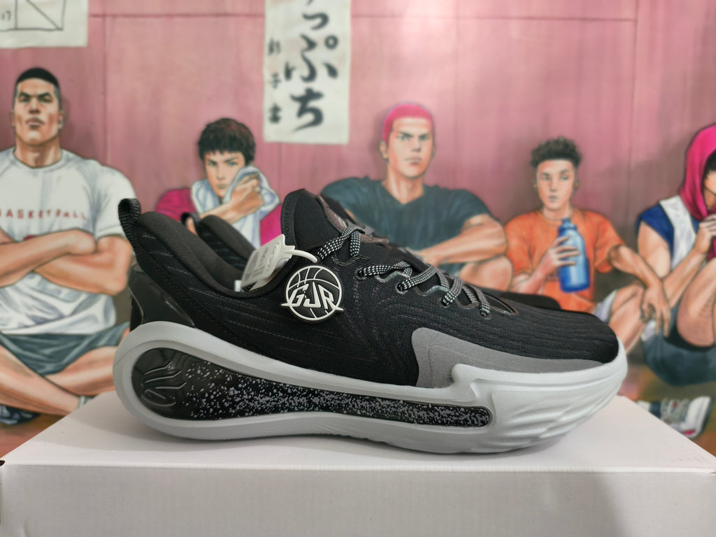 Side view of a black and gray basketball shoe with a basketball emblem.