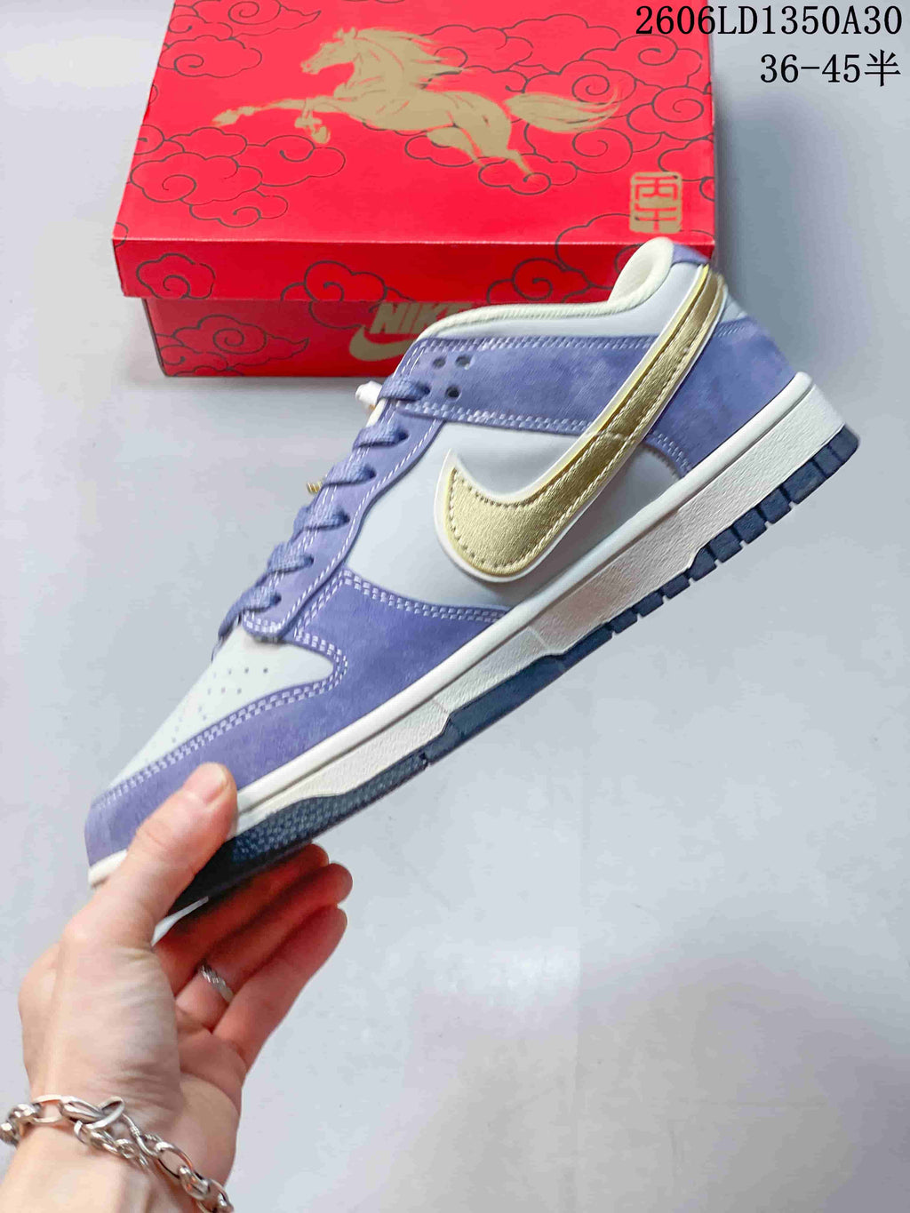 Side view of the lavender and light gray Nike SB Dunk Low with gold Swoosh detail.