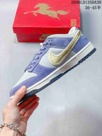 Side view of the lavender and light gray Nike SB Dunk Low with gold Swoosh detail.
