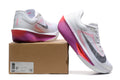White Nike Zoom Fly 6 shoes with pink and purple accents beside a box showing a sample size label