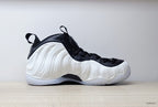 Side profile of a white Nike Little Posite One GS sneaker with black trim