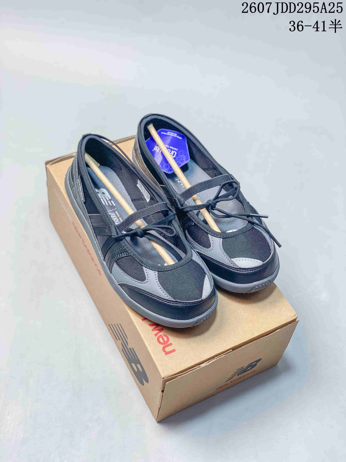 Pair of black and gray New Balance sneakers displayed on a New Balance shoe box, with the style code and size range visible above.