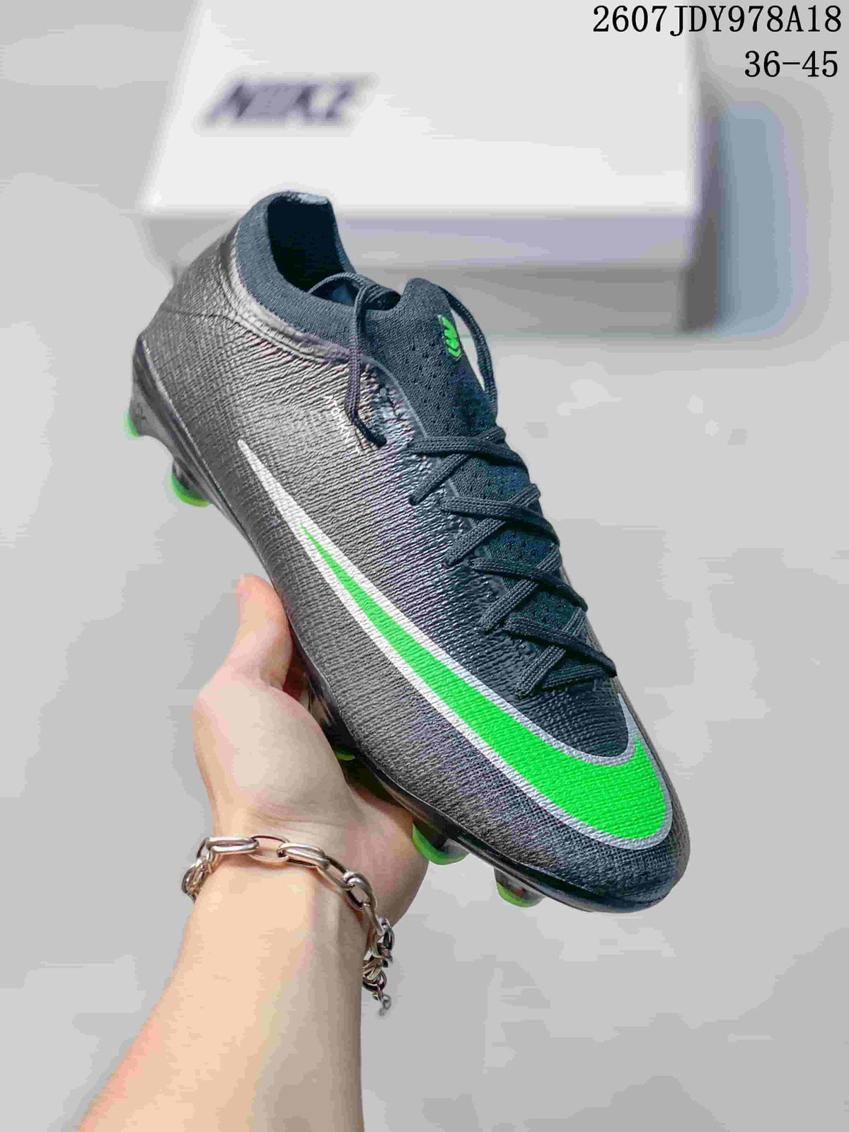 Angled side view showing the black textured upper, green-and-white Swoosh, laces, and outsole studs.