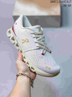 Angled side view of the white sneaker showing the knit-style upper, gold branding, and segmented outsole.