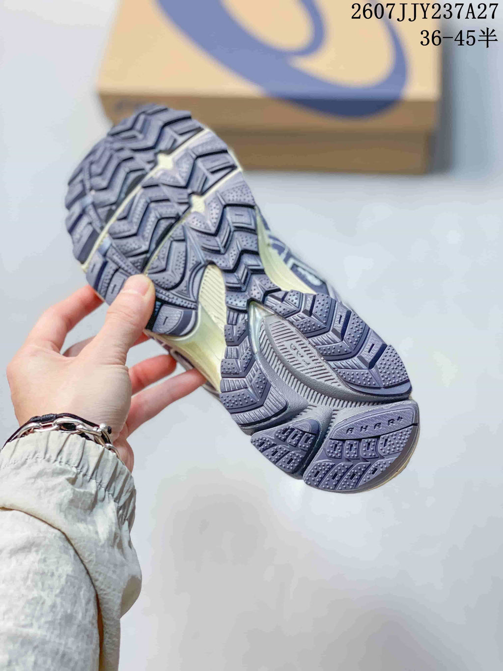 Close view of the sneaker outsole showing a deep, patterned tread in gray and dark purple.