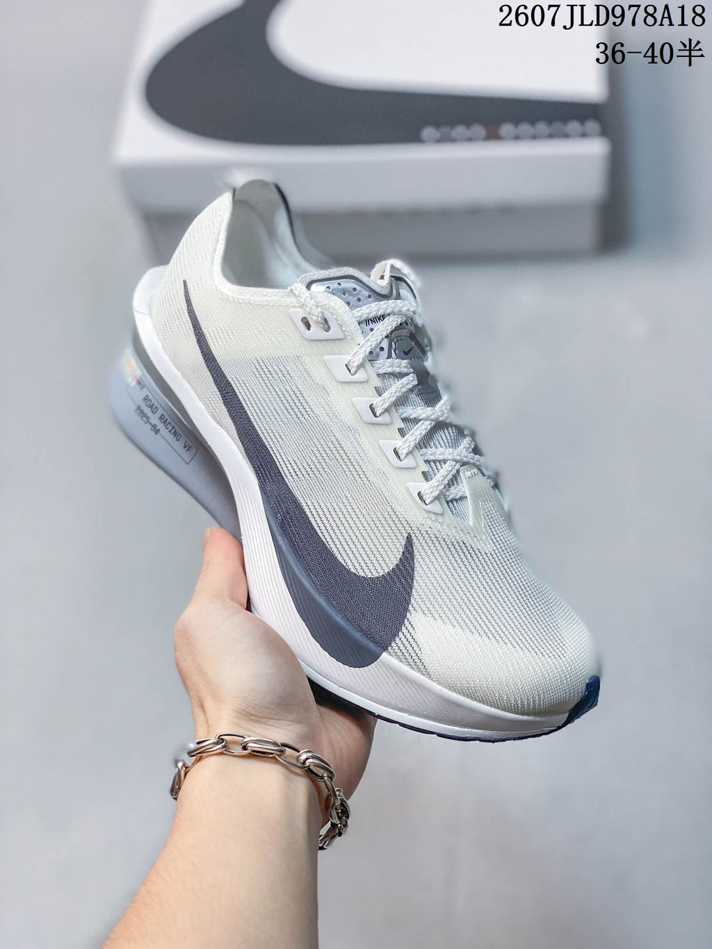 Light-colored Nike racing sneaker with dark side branding and mostly white and gray details; image text shows style code 2607JLD978A18 and size range 36–40.