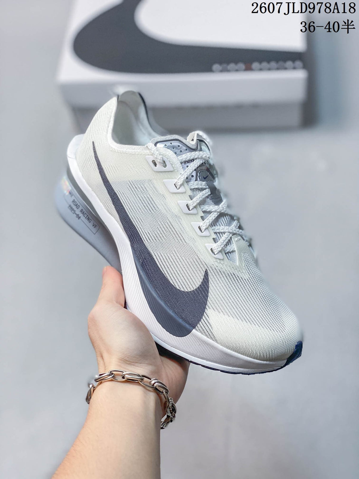 Light-colored Nike racing sneaker with dark side branding and mostly white and gray details; image text shows style code 2607JLD978A18 and size range 36–40.