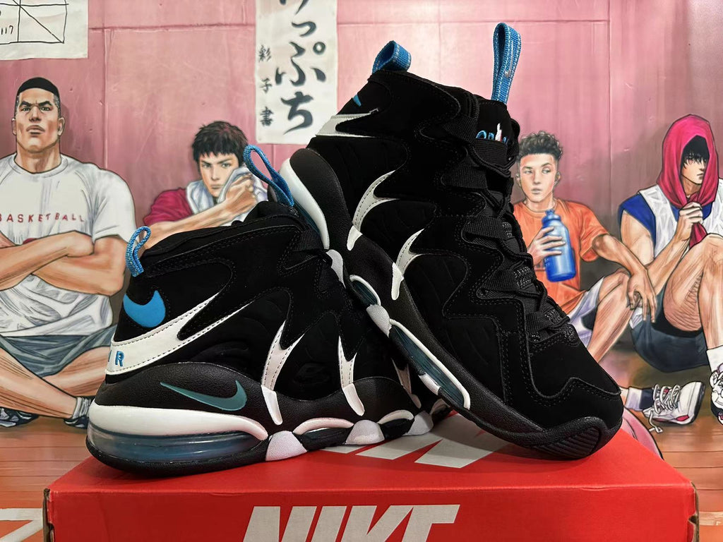 Angled view of black basketball shoes showing layered side panels, white details, blue accents, and visible cushioning.