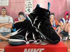 Angled view of black basketball shoes showing layered side panels, white details, blue accents, and visible cushioning.
