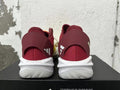 Rear view of yellow, orange, and burgundy adidas Adizero sneakers with white sculpted soles.