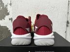 Rear view of yellow, orange, and burgundy adidas Adizero sneakers with white sculpted soles.