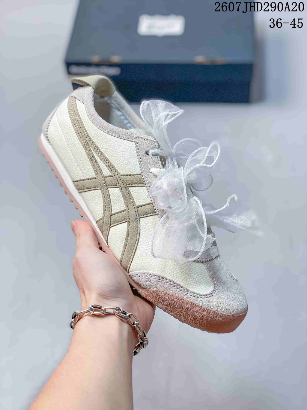 White sneaker with beige side stripes, gray toe detailing, and a tan outsole.
