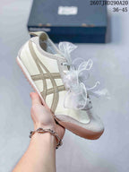 White sneaker with beige side stripes, gray toe detailing, and a tan outsole.