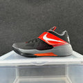 Side view of a black and gray Nike basketball shoe with red accents, a forefoot strap, and a white side logo.