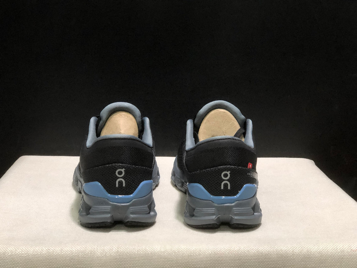Rear view showing the padded collars, On logos, blue heel panels, and gray outsoles.