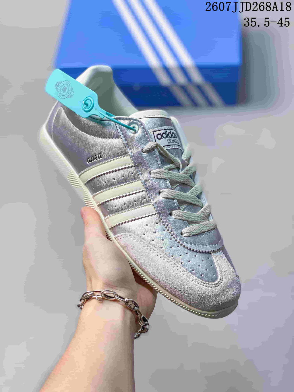 Angled close view of the silver and white sneaker showing the lace-up construction, perforated toe, side stripes, and Changle branding.