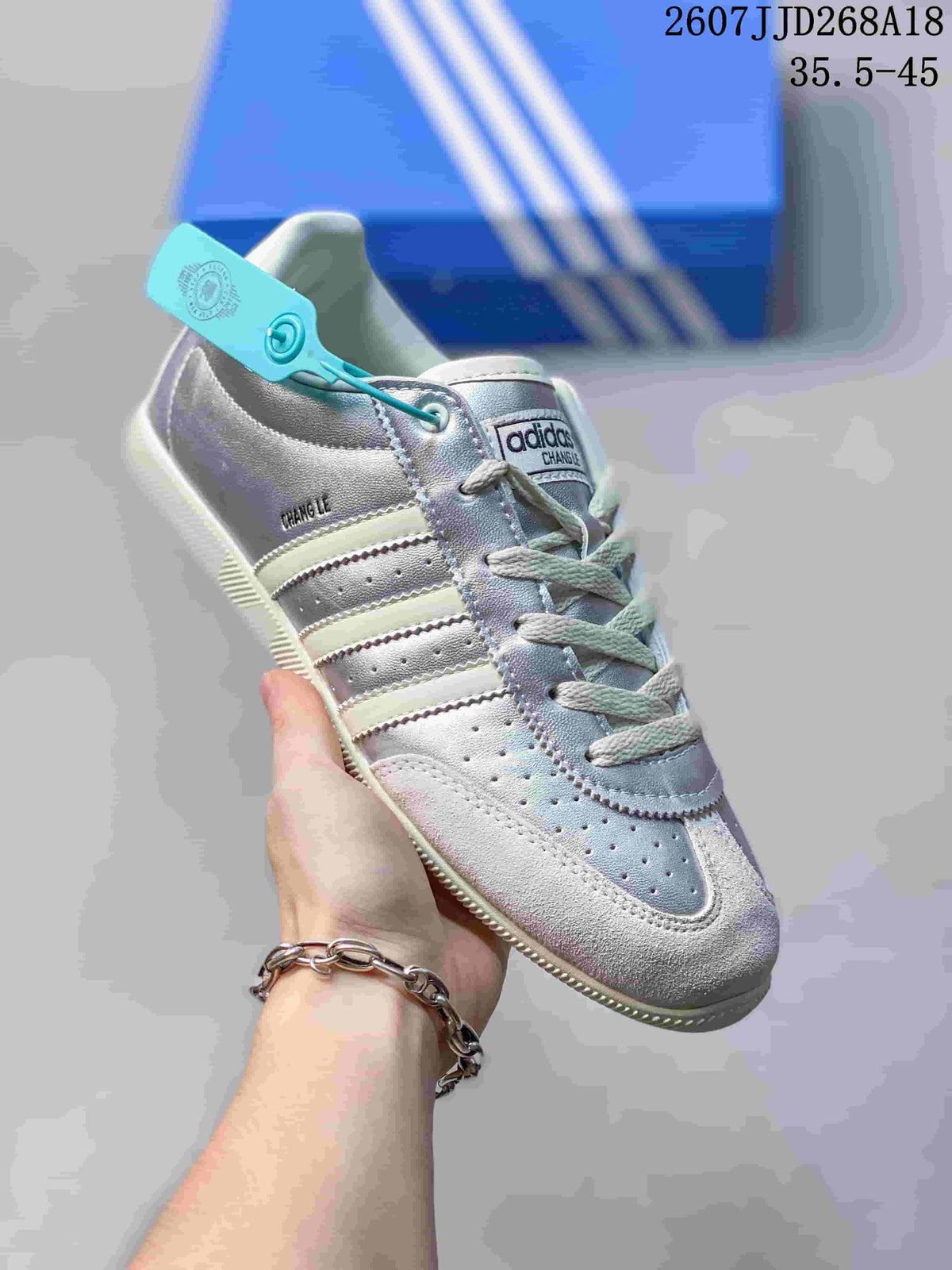 Angled close view of the silver and white sneaker showing the lace-up construction, perforated toe, side stripes, and Changle branding.