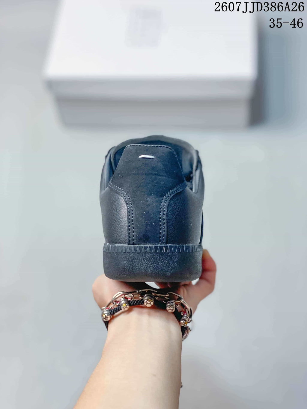 Rear view of a black low-top sneaker showing the stitched heel panel, padded collar, and rubber outsole.