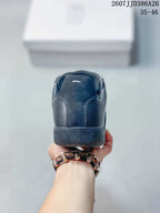 Rear view of a black low-top sneaker showing the stitched heel panel, padded collar, and rubber outsole.