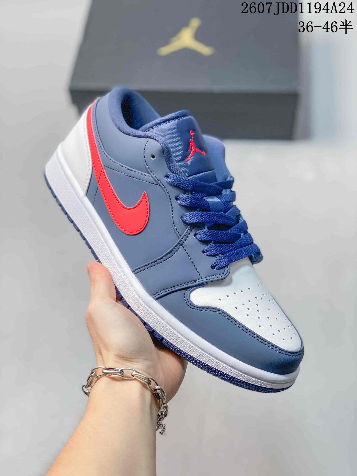 Navy, white, and red low-top Jordan sneaker shown from a front three-quarter angle, with a bright red side logo and navy laces.