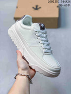 Angled side view of the white DESCENTE sneaker showing the textured upper, lace-up construction, raised sole, and branded sidewall.