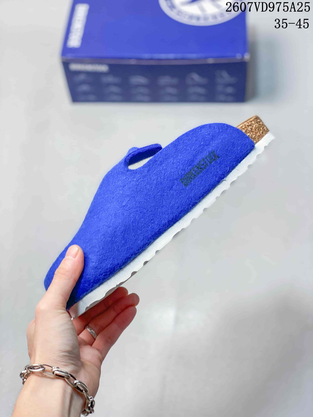Side view of a blue closed-toe clog showing the textured upper, tan heel detail and white outsole.