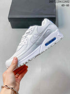 Side view of a white Nike Air Max 90 sneaker with a blue heel detail