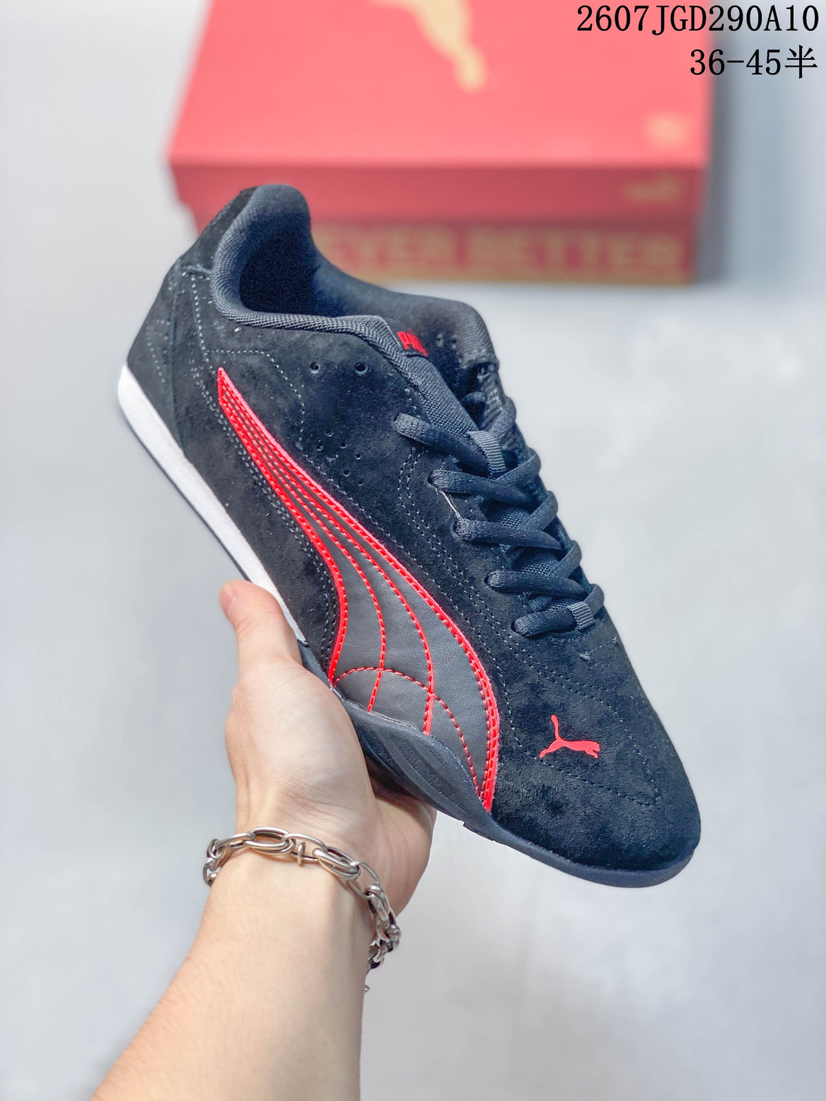 Angled side view of the black and red Puma low-top sneaker with its lace-up front and red side detailing.