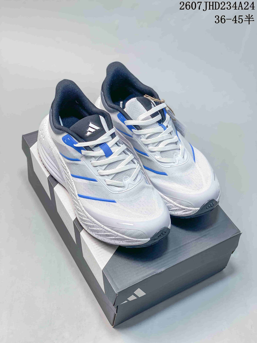 Pair of white and blue adidas low-top sneakers displayed on a shoebox.