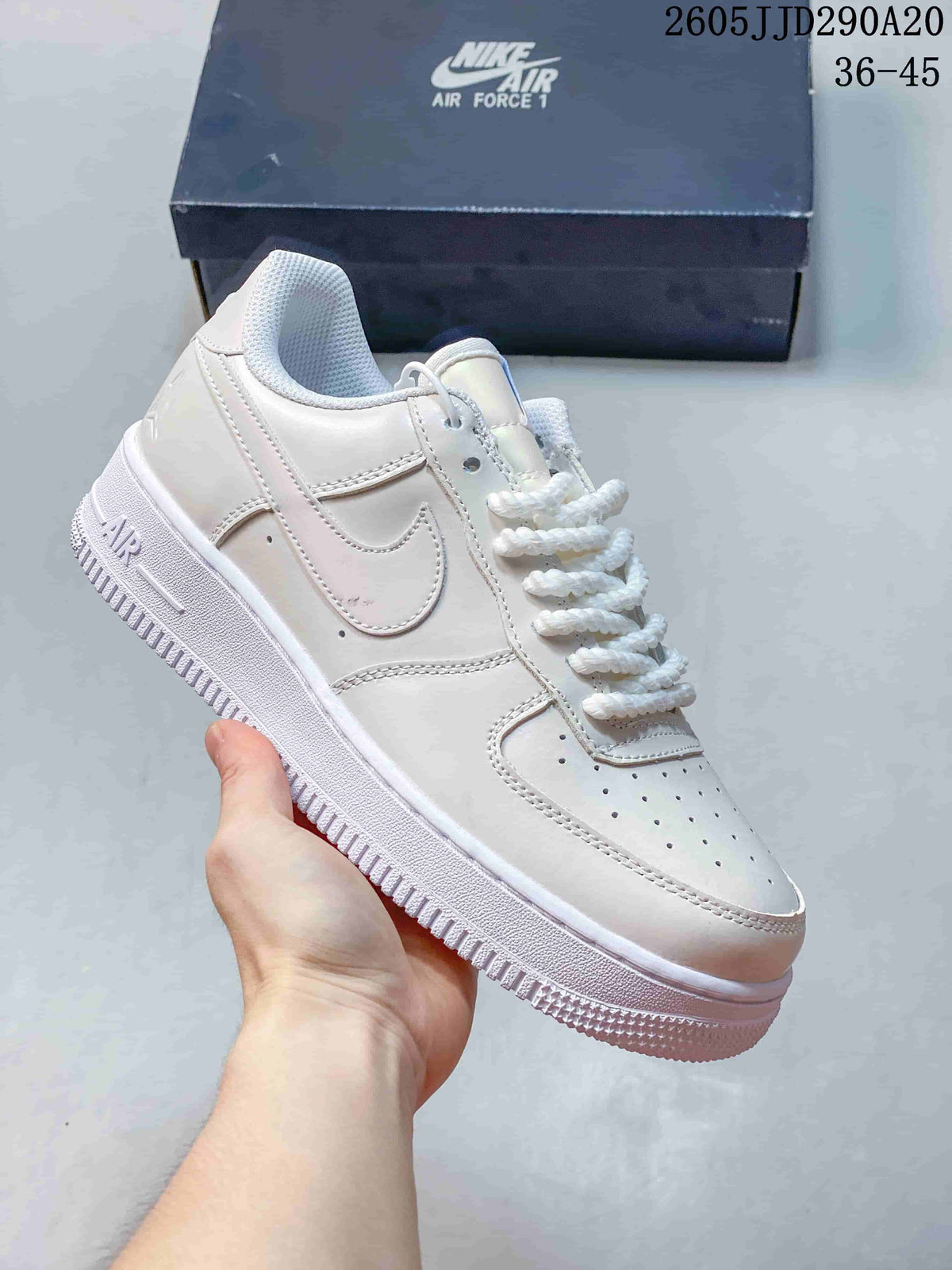 Close-up of an all-white Nike Air Force 1-style sneaker with perforated toe box and white rope-style laces.